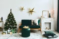 Stylish christmas living room interior with green sofa, white chimney, christmas tree and wreath, stars, gifts and decoration. Royalty Free Stock Photo