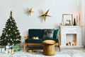 Stylish christmas living room interior with green sofa, white chimney, christmas tree and wreath, stars, gifts and decoration. Royalty Free Stock Photo