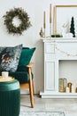 Stylish christmas living room interior with green sofa, white chimney, christmas tree and wreath, stars, gifts and decoration. Royalty Free Stock Photo