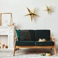 Stylish christmas living room interior with green sofa, white chimney, christmas tree and wreath, stars, gifts and decoration. Royalty Free Stock Photo