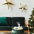 Stylish christmas living room interior with green sofa, white chimney, christmas tree and wreath, stars, gifts and decoration. Royalty Free Stock Photo