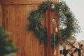 Stylish christmas rustic wreath with vintage bells and ribbon hanging on brass handle on wooden front door close up. Modern eco Royalty Free Stock Photo