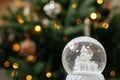 Stylish christmas snow globe on background of christmas tree in lights in festive decorated boho room. Snowy white snow globe Royalty Free Stock Photo