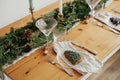 Stylish Christmas table setting. Christmas tree cookie on plate, linen napkin with bell, vintage cutlery, wineglass, fir branches