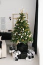 Stylish Christmas tree with black and white toys, which stands on an iron barrel in the living room of the house Royalty Free Stock Photo