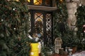 Stylish christmas tree with red berries, wreath on doors and wooden sleigh at front of store at holiday market in city street. Royalty Free Stock Photo