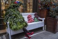 Stylish Christmas tree with woman's legs in black tights and red shoes sits on a white bench