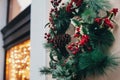 Stylish christmas wreath with red berries,ornaments, pine cones, branches on building in european city street. Festive decoration Royalty Free Stock Photo