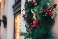 Stylish christmas wreath with red berries,ornaments, pine cones, branches on building in european city street. Festive decoration Royalty Free Stock Photo