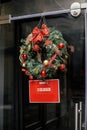 Stylish christmas wreath red bow and baubles and Sorry we closed sign on doors of building. Modern christmas decor in city street Royalty Free Stock Photo