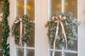 Stylish Christmas wreath with a satin bow on the white entrance doors of a country house Royalty Free Stock Photo