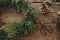 Stylish christmas wreath with spruce branches and berries, scissors, pine cones, candles, ornaments on rustic wooden background. Royalty Free Stock Photo