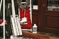 Stylish christmas wreath, white wooden sleigh and ice skate at front of store at holiday market in city street. Christmas street