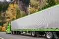 Stylish classic green big rig semi truck tractor carry cargo in shiny refrigerator semi truck driving on the highway road with Royalty Free Stock Photo