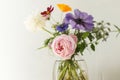 Stylish colorful flowers bouquet on rustic wall background. Beautiful summer wildflowers, anemones and roses in vase gathered from Royalty Free Stock Photo