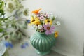 Stylish colorful wildflowers bouquet on tile shelf on rustic wall background. Beautiful summer flowers in vase gathered from Royalty Free Stock Photo