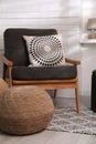 Stylish comfortable pouf near armchair in room. Home design