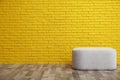 Stylish comfortable pouf near yellow brick wall, space for text. Interior design