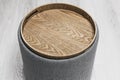 Stylish comfortable round padded stool with wooden top. cylindrical padded stool upholstered with gray fabric Royalty Free Stock Photo