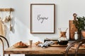 Stylish composition of cozy dining room interior with mock up poster frame, wooden family dining table, plants and vintage.