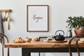 Stylish composition of cozy dining room interior with mock up poster frame, wooden family dining table, plants and vintage.