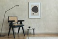 Stylish composition of cozy living room interior with mock up poster frame, wooden armchair, black modern lamp and black tiny. Royalty Free Stock Photo