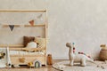 Stylish composition of cozy scandinavian child`s room interior with wooden bed, pillows, plush dinosaur, wooden toys and textile.
