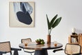 Stylish composition of dining room interior with design table, modern chairs, decoration, tropical leaf in vase, fruits, abstract. Royalty Free Stock Photo