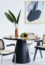 Stylish composition of dining room interior with design table, modern chairs, decoration, tropical leaf in vase, fruits. Royalty Free Stock Photo