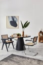 Stylish composition of dining room interior with design table, modern chairs, decoration, tropical leaf in vase, fruits, bookcase. Royalty Free Stock Photo