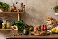 Stylish composition of kitchen interior with family table, vegetables, tea pot, dessert, food supplies, plants.