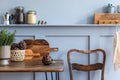 Stylish composition of kitchen interior with wooden family table, chairs, vegetables, herbs, plants, fruits, food supplies. Royalty Free Stock Photo