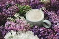 Stylish composition of lilac flowers and warm cup of coffee. Colorful lilac branches and coffee with creamy foam, good morning