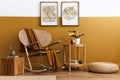 Stylish composition of living room interior with design rattan armchair, two mock up poster frames, plants, cube.