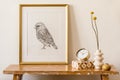 Stylish composition of living room interior with gold mock up frame, wooden bench, gold clock, box, dried flowers in vase Royalty Free Stock Photo