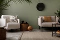 Stylish composition of living room interior with green wall, grey sofa with brown pillow. White armchair with patterned pilow,