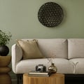 Stylish composition of living room interior with green wall, grey sofa with grey pillow. White armchair with patterned pilow,