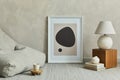 Stylish composition of minimalistic living room interior with mock up poster frame, grey pouf, white lamp on wooden cube.