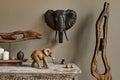 Stylish composition at moroccan interior with wooden shlef, candles, design elephant figure and decoration in modern home decor.