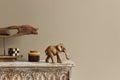 Stylish composition at moroccan interior with wooden shlef, cube, design elephant figure and decoration in modern home decor.