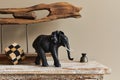 Stylish composition at moroccan interior with wooden shlef, cube, design elephant figure and decoration in modern home decor.