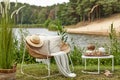 Stylish composition of outdoor garden on the lake with design rattan armchair, coffee table, plaid, pillows, drinks and elegant Royalty Free Stock Photo