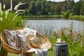 Stylish composition of outdoor garden on the lake with design rattan armchair, coffee table, plaid, pillows, drink. Elegant. Royalty Free Stock Photo