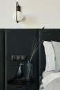 Stylish composition of small modern bedroom interior. Bed, creative lamp and black elegant personal accessories. Walls with black.