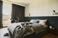 Stylish composition of small modern bedroom interior. Bed, creative lamp and elegant personal accessories.Walls with black panels. Royalty Free Stock Photo