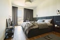 Stylish composition of small modern bedroom interior. Bed and elegant personal accessories. Walls with black panels.
