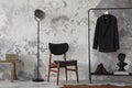 The stylish compostion at living room interior with concrete wall, chair, hanger with clothes and elegant personal accessories. Royalty Free Stock Photo