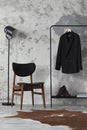 The stylish compostion at living room interior with concrete wall, chair, hanger with clothes and elegant personal accessories. Royalty Free Stock Photo