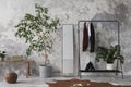 The stylish compostion at living room interior with concrete wall, hanger mirror, wooden bench and elegant personal accessories. Royalty Free Stock Photo