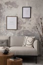 The stylish compostion at living room interior with design gray sofa, coffee table, posters and elegant personal accessories. Loft